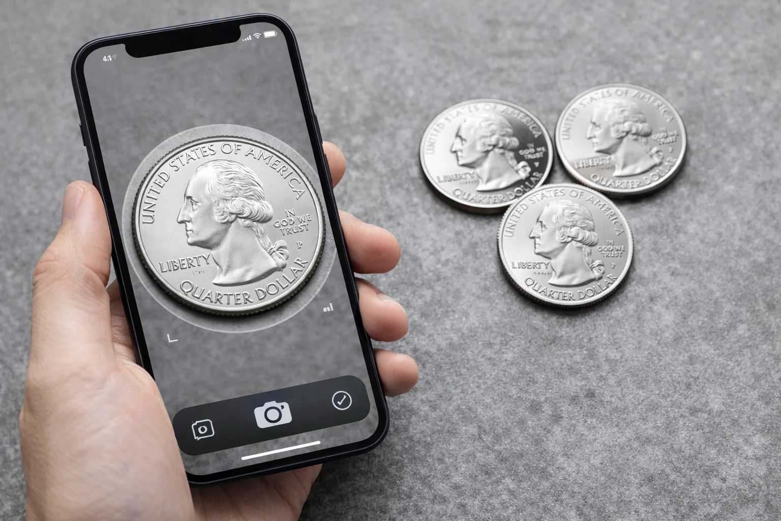 Smartphone scanning a 2017 quarter beside three coins on a table.